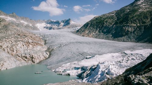 Free Scenic view of a glacier flowing into a serene lake surrounded by rocky mountains. Stock Photo