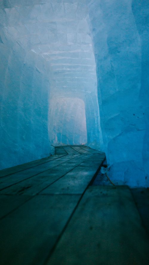 Free Explore the magical ice cave passage with a wooden walkway in Obergoms, Switzerland. Stock Photo