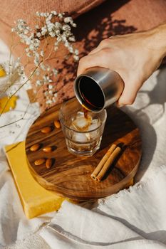 咖啡倾倒的场景美观，配有玻璃杯、冰块、杏仁、肉桂和乡村风格的装饰