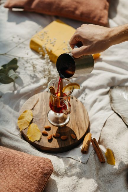 Warm mulled wine being poured with cinnamon and almonds on a rustic tray for a cozy fall setting.
