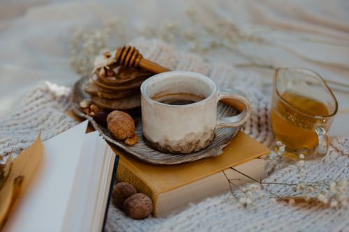 Free A rustic breakfast setup with a ceramic cup of coffee, pancakes, and honey outdoors in warm lighting. Stock Photo
