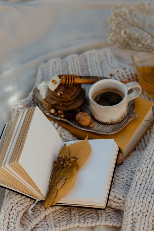 Free Warm autumn composition featuring an open book, coffee, and pastries on a knitted blanket. Stock Photo
