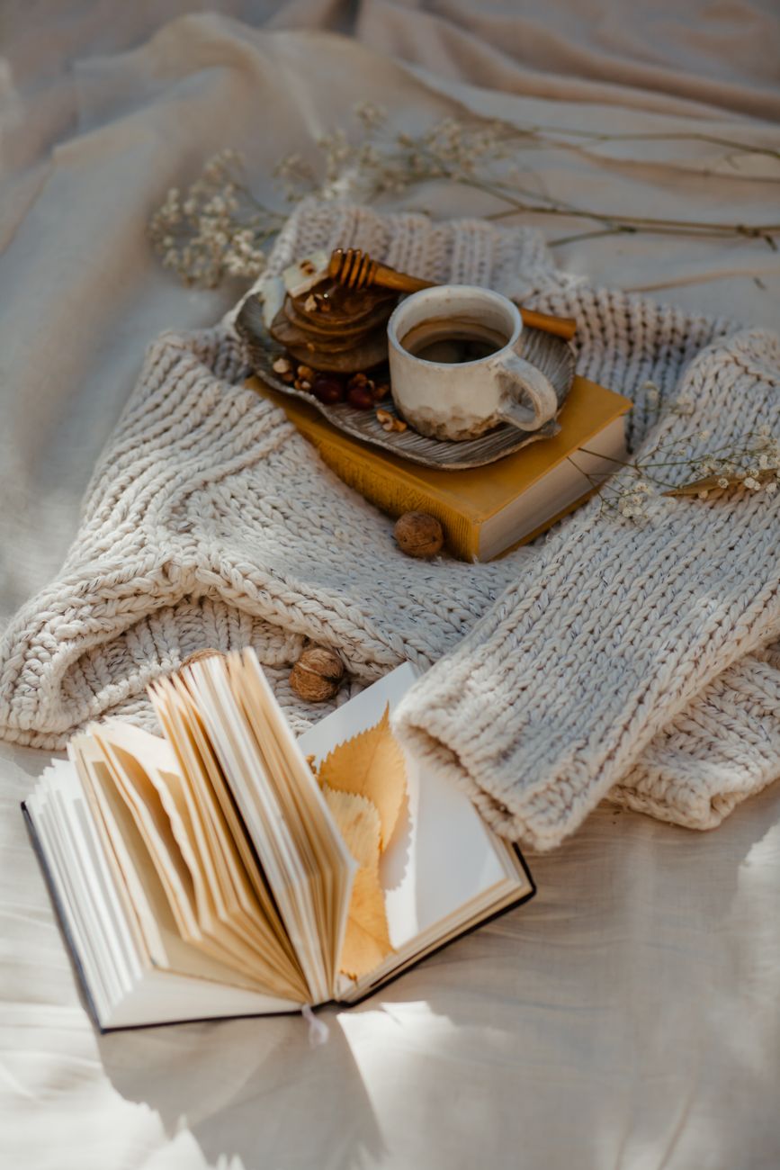 Warm cozy scene with coffee and an open book on knitted fabric, perfect for autumn inspiration.