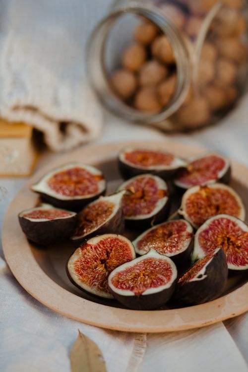 Free A rustic still life showcasing fresh sliced figs on a wooden plate, evoking natural warmth. Stock Photo