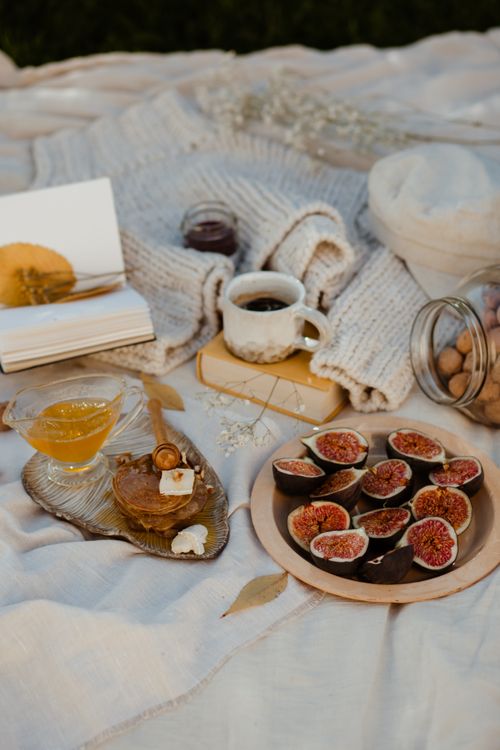 Free A warm, rustic still life of figs, honey, and tea on a blanket, evoking cozy autumn vibes. Stock Photo