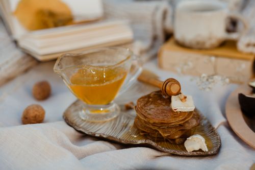 Free A cozy breakfast setting featuring pancakes, honey, and butter on a rustic tray. Stock Photo