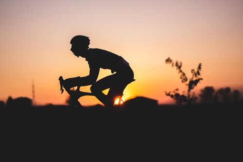 Free Cyclist silhouette against a vibrant sunset, embodying freedom and adventure. Stock Photo