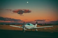 Small airplane on airfield in countryside against sundown sky