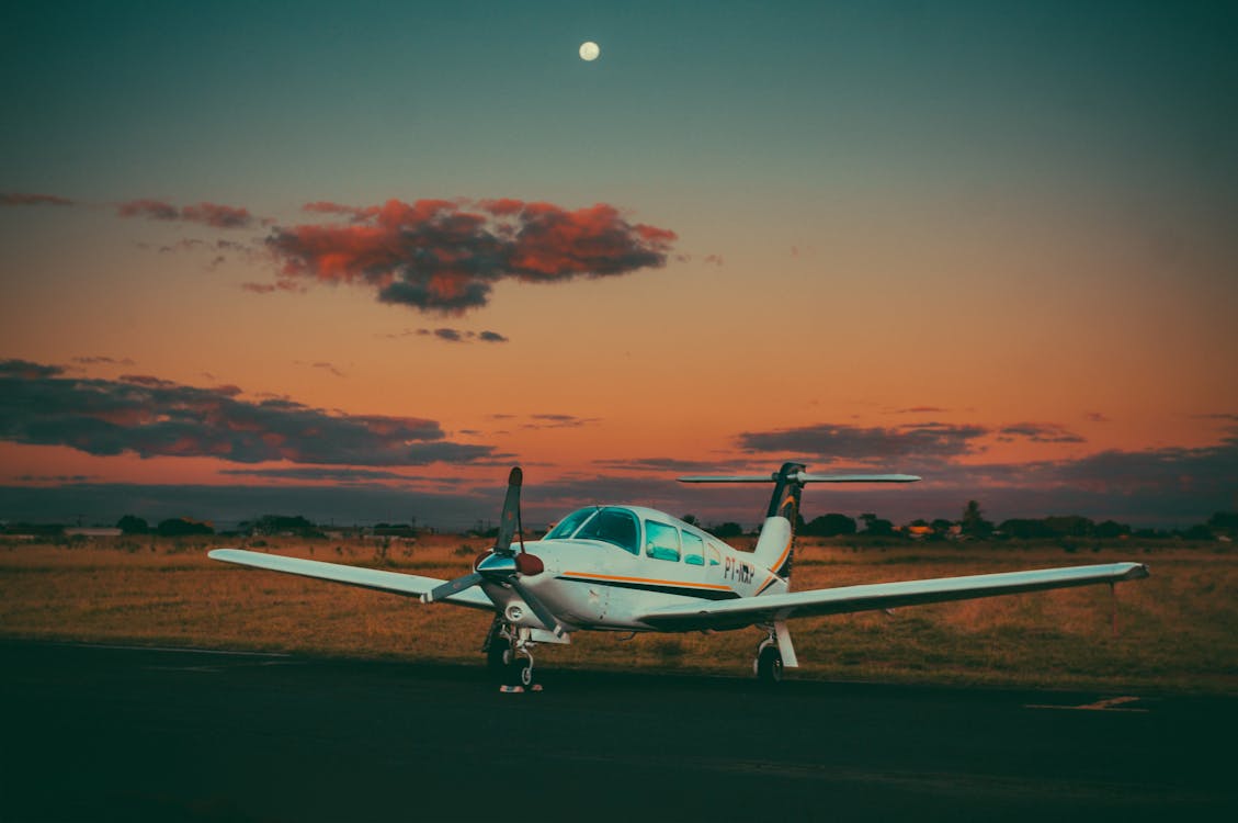 Small airplane on airfield in countryside against sundown sky