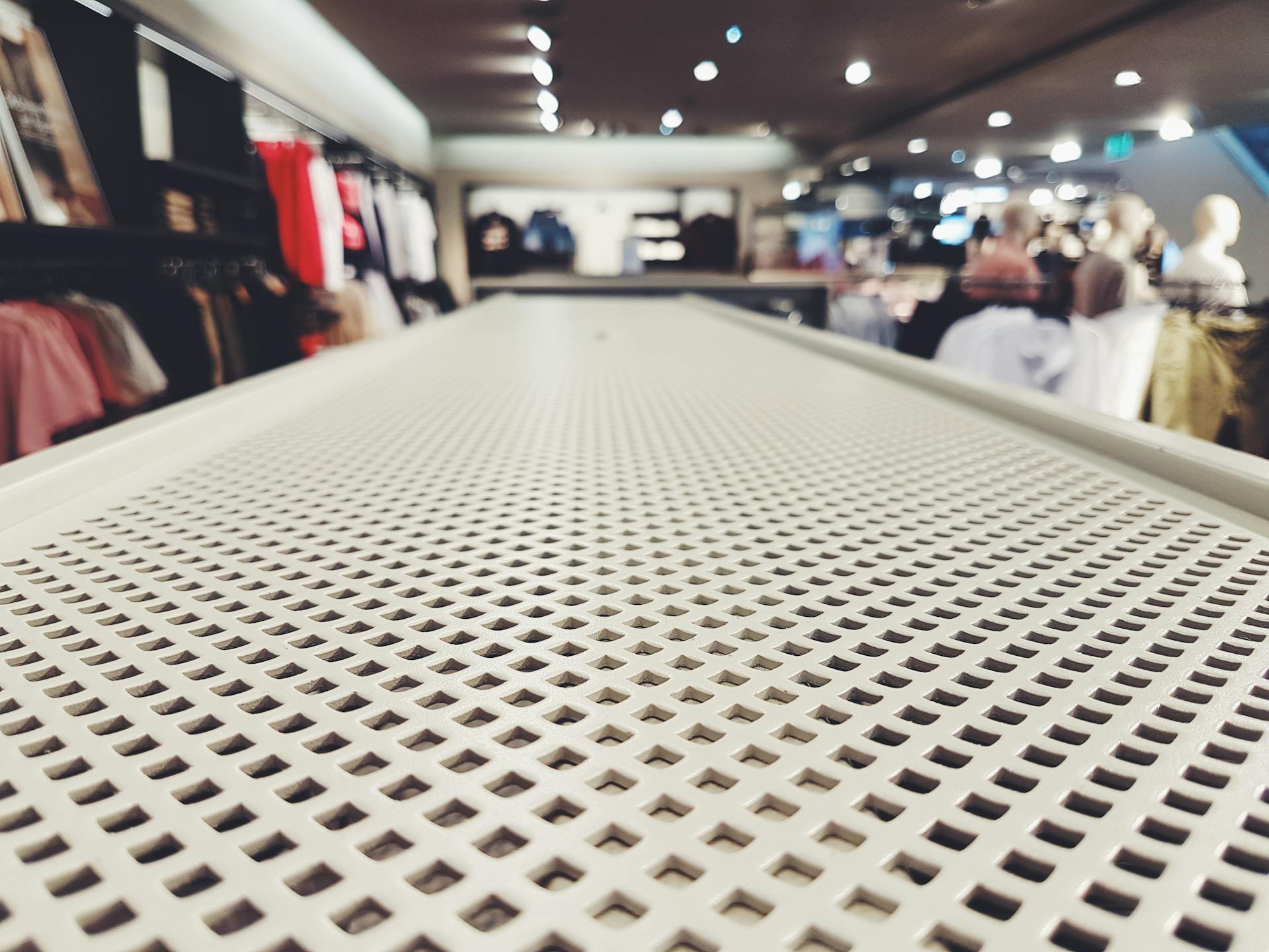 A modern clothing store interior with a focus on a patterned shelf and blurred mannequins. Ideal for retail and fashion.