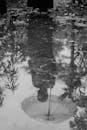 Grayscale Photo of Person's Reflection on Water