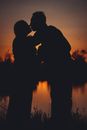 Silhouettes of unrecognizable couple kissing in sunset