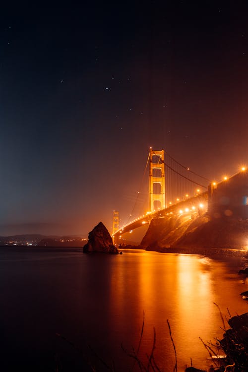 Illuminated Golden Gate Bridge above calm water at night