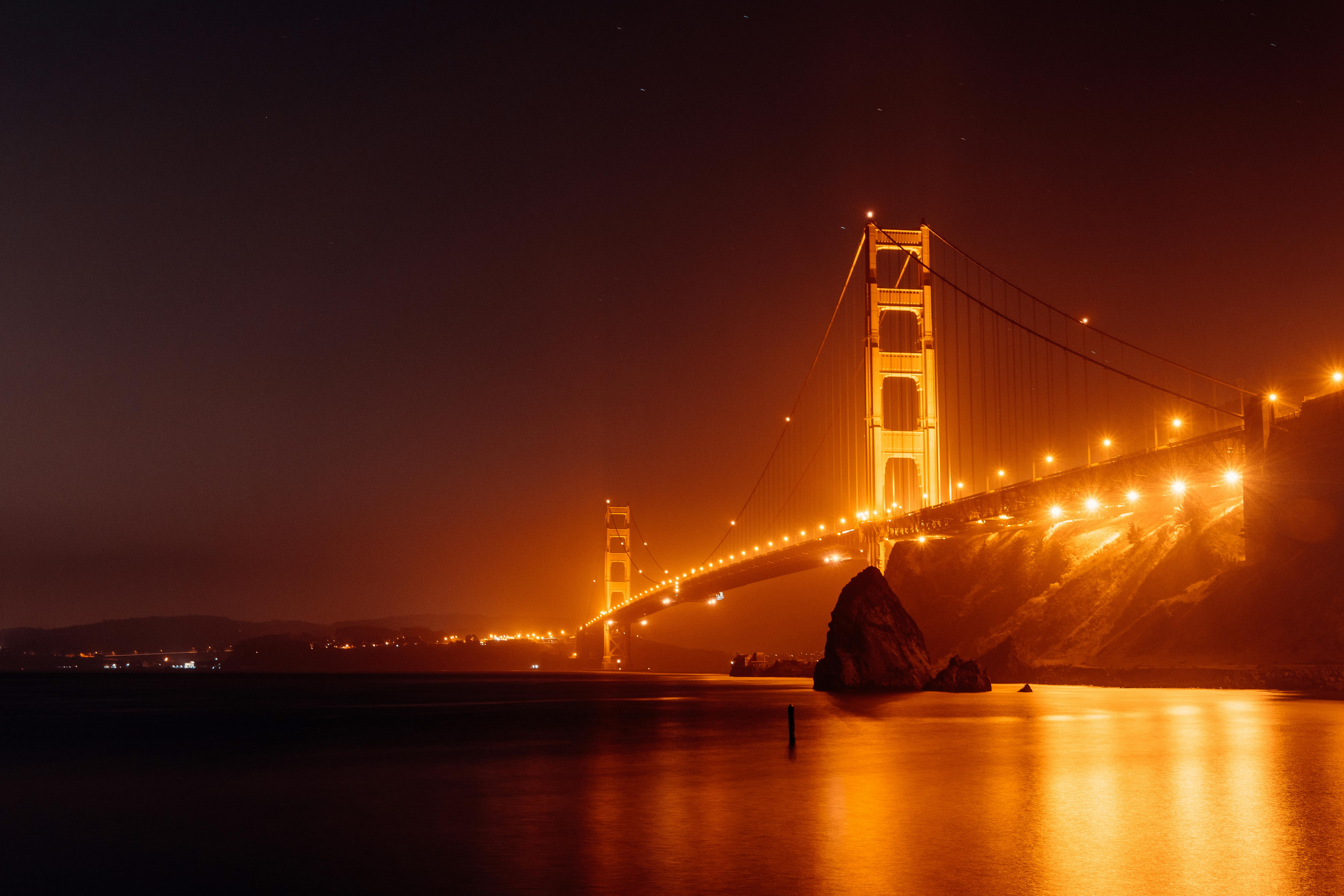 Bright Golden Gate Bridge above water at night