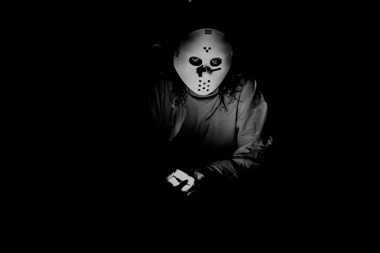 a mysterious figure wearing a mask illuminated in low light creating a