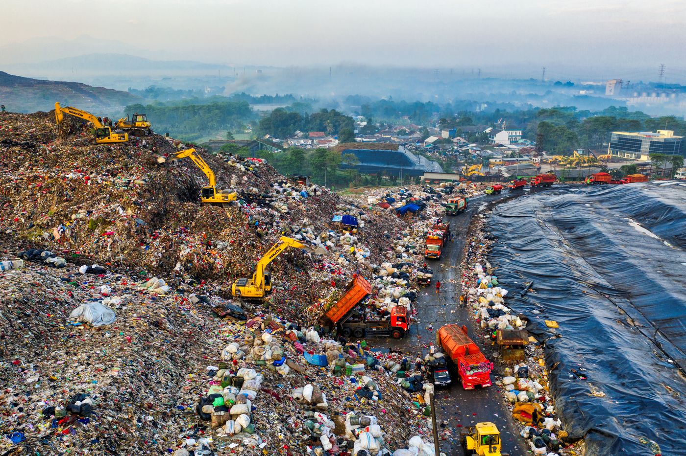 An unlined landfill seen from above at the edge of open water