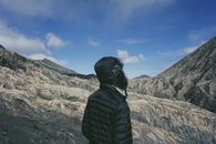 Man in Black Jacket Standing on Brown Rock Mountain Under Blue Sky