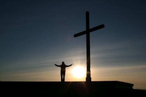 Silueta De Persona De Pie Junto A La Cruz Durante La Puesta De Sol