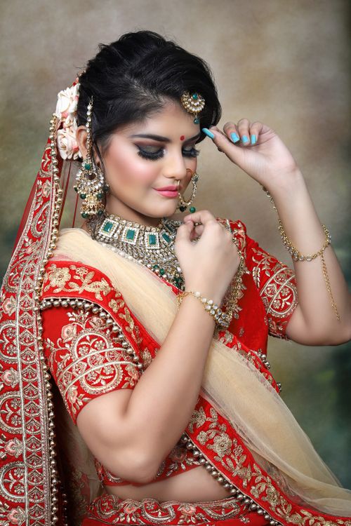 Free Thoughtful young Indian female in traditional bridal clothes and sari with makeup and big necklace with piercing and earrings with veil and bracelets with closed eyes Stock Photo