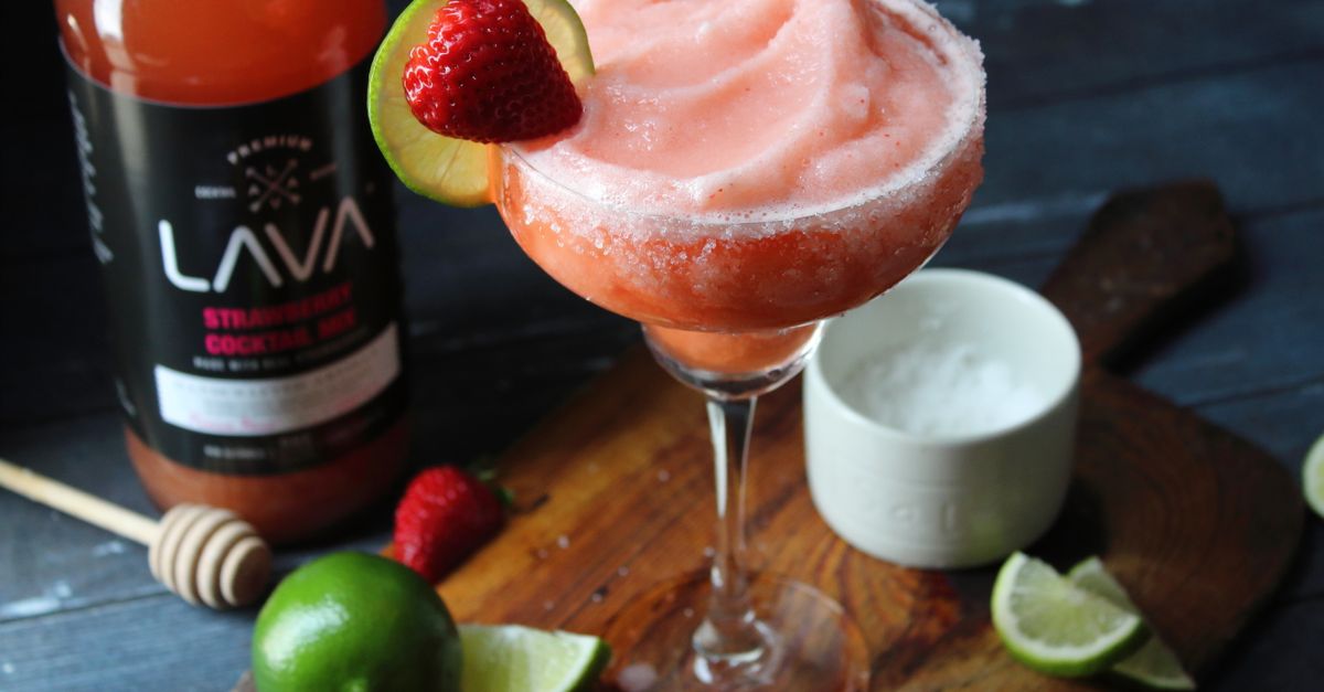 Chilled strawberry margarita with lime and strawberry garnish on wooden board. Perfect for cocktail enthusiasts.