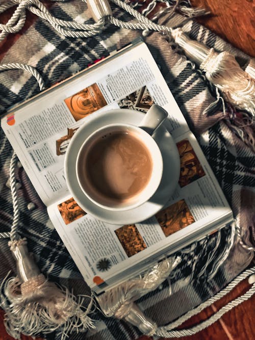 Free Coffee on a Ceramic Mug on Top of an Open Book  Stock Photo