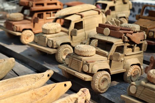 A selection of intricately carved wooden toy trucks displayed at a market. Perfect for souvenirs.