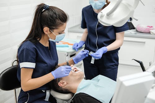 Dentista Con Asistente Curando Los Dientes Del Paciente