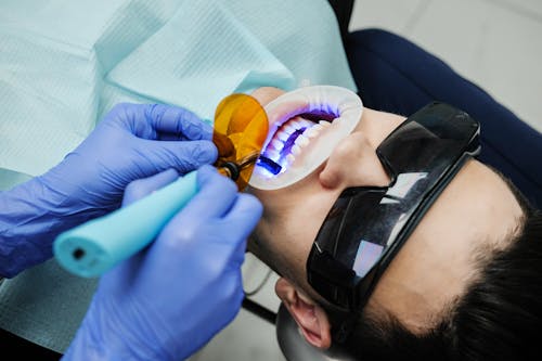 Dentista Haciendo Examen Oral Del Paciente Con Equipo De Luz Ultravioleta
