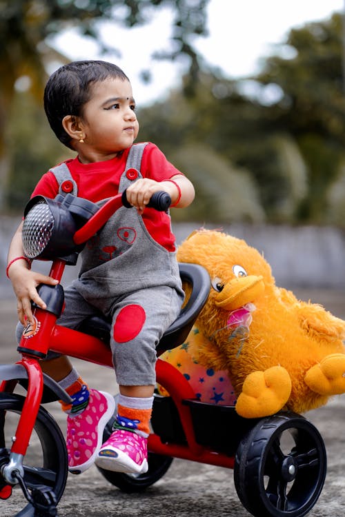 Free Cute Child riding a Bike Toy carrying Stuffed Toys Stock Photo