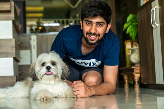 Smiling man with Shih Tzu dog indoors, showcasing companionship and happiness.