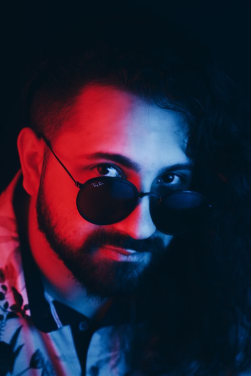 Free High angle of serious confident man with beard wearing sunglasses in red light Stock Photo