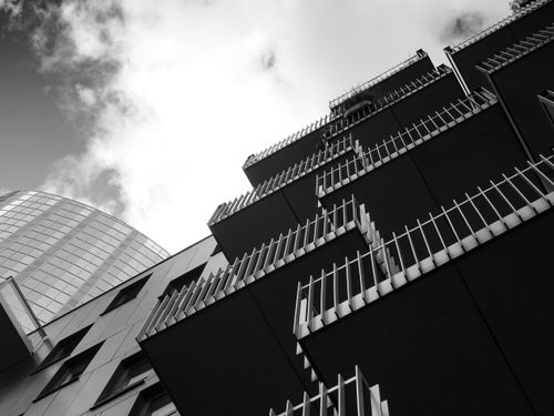 Free Low angle view of futuristic urban buildings with unique architectural design in black and white. Stock Photo