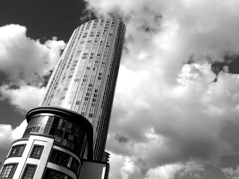 这张黑白照片中，一座光滑的摩天大楼直插多云天空，突显了现代建筑的特色
