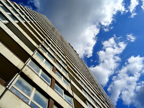 从戏剧性的低角度仰望现代摩天大楼，玻璃与钢铁建筑在明亮的蓝天下熠熠生辉