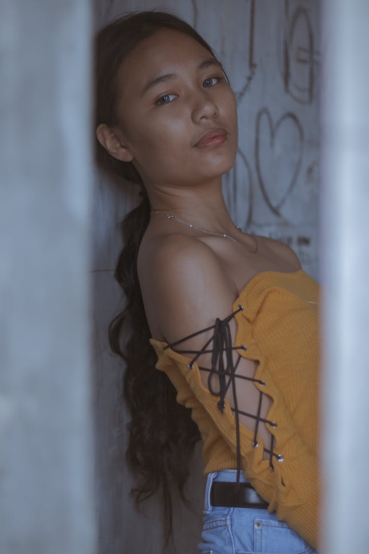 Tanned Girl In Fashionable Outfit Leaning On Wall