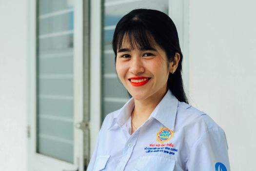 Portrait of a smiling woman in a white shirt standing indoors, exuding confidence.