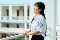 Woman in White Button Up Shirt Holding on a Metal Railing while Looking Afar