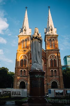 从低角度仰望蓝天下的圣母玛利亚雕像，背景是大教堂的尖顶