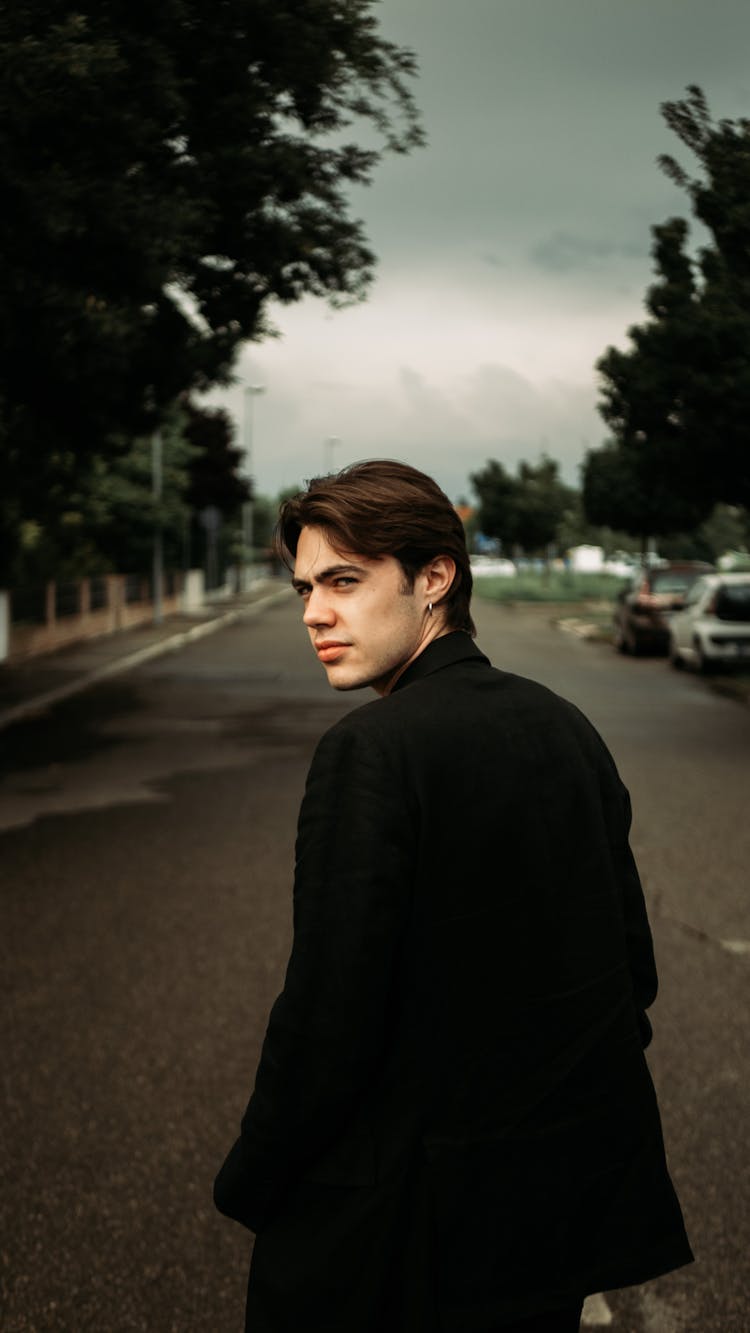 Young Confident Man In Black Jacket Walking Along Street