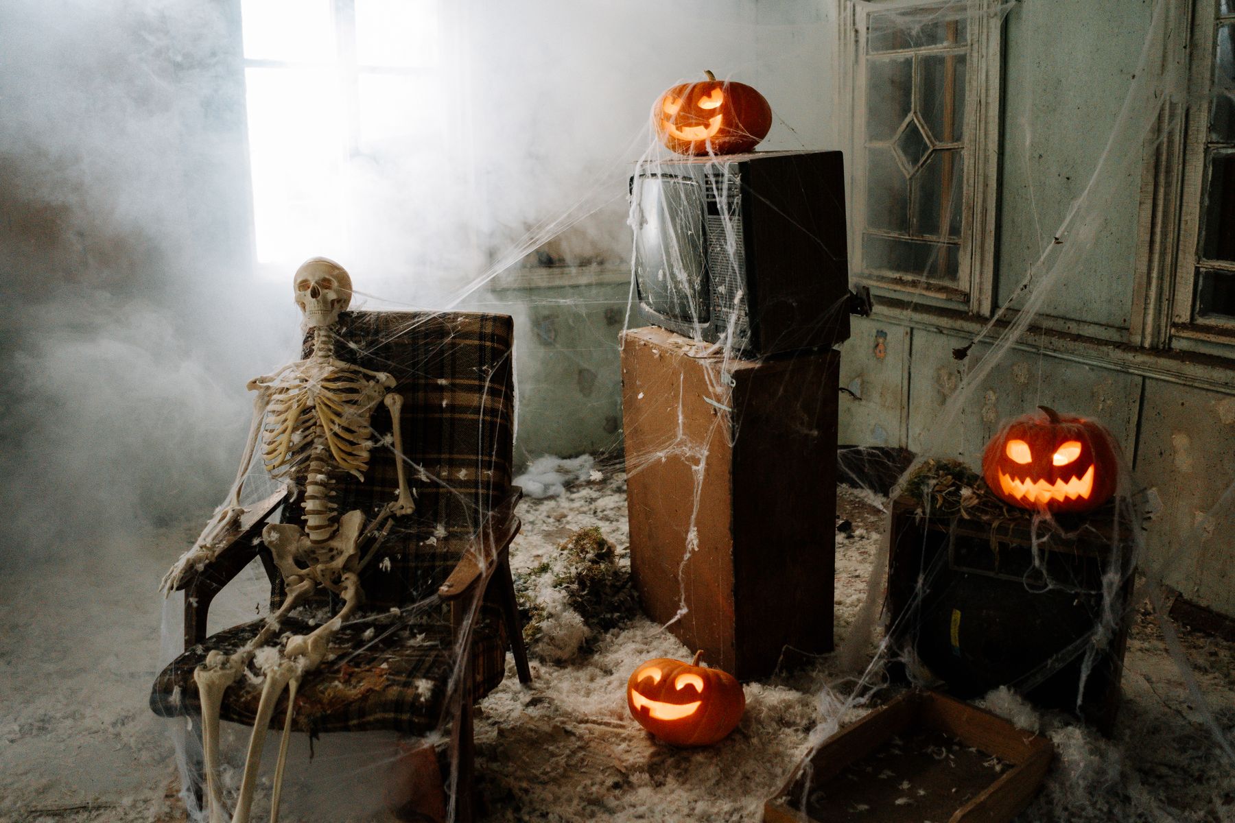 Spooky Halloween-decorated indoor setting with skeleton, pumpkins and cobweb details