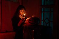 一名妇女在光线昏暗、阴森的环境中点燃了南瓜灯