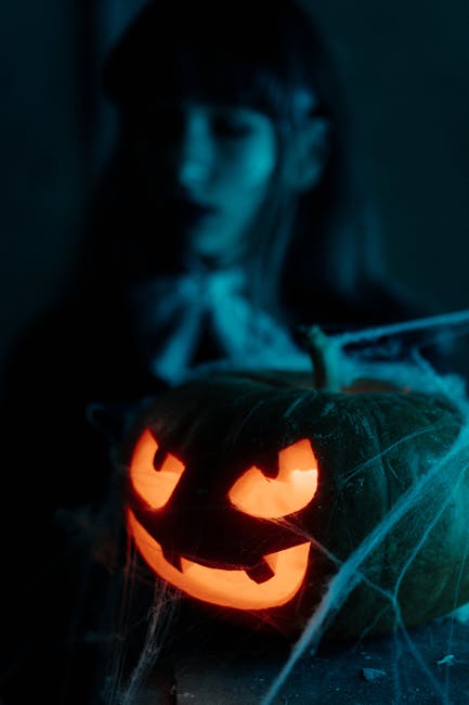 Creepy illuminated jack-o'-lantern with cobwebs in dark ambiance, perfect for Halloween.