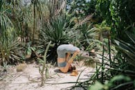 A woman performing a headstand yoga pose outdoors in a vibrant, lush garden setting.