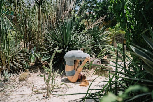 A woman performing a headstand yoga pose outdoors in a vibrant, lush garden setting.