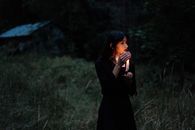 黑暗的森林里，一个举着蜡烛的女人让人产生一种神秘而怪异的感觉