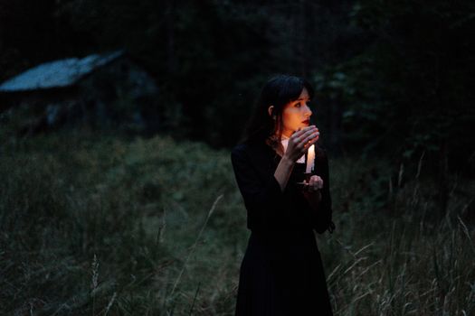 黑暗的森林里，一个举着蜡烛的女人让人产生一种神秘而怪异的感觉