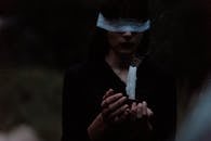 一个蒙眼女子手持蜡烛的神秘场景，营造出一种怪诞的仪式氛围