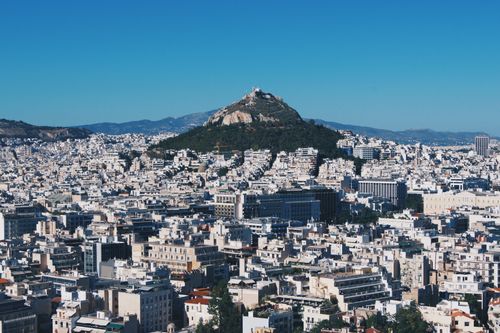 Free Stunning aerial shot of Athens, showcasing Lycabettus Hill amid the city's vast skyline under a clear blue sky. Stock Photo