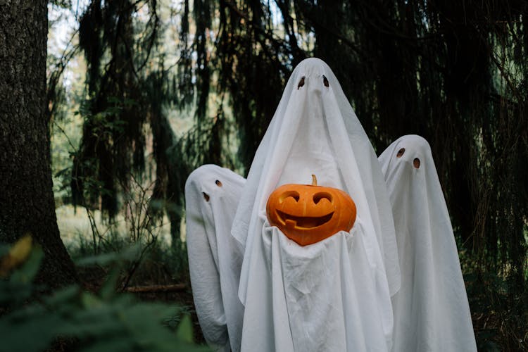 Ghosts Holding A Carved Pumpkin