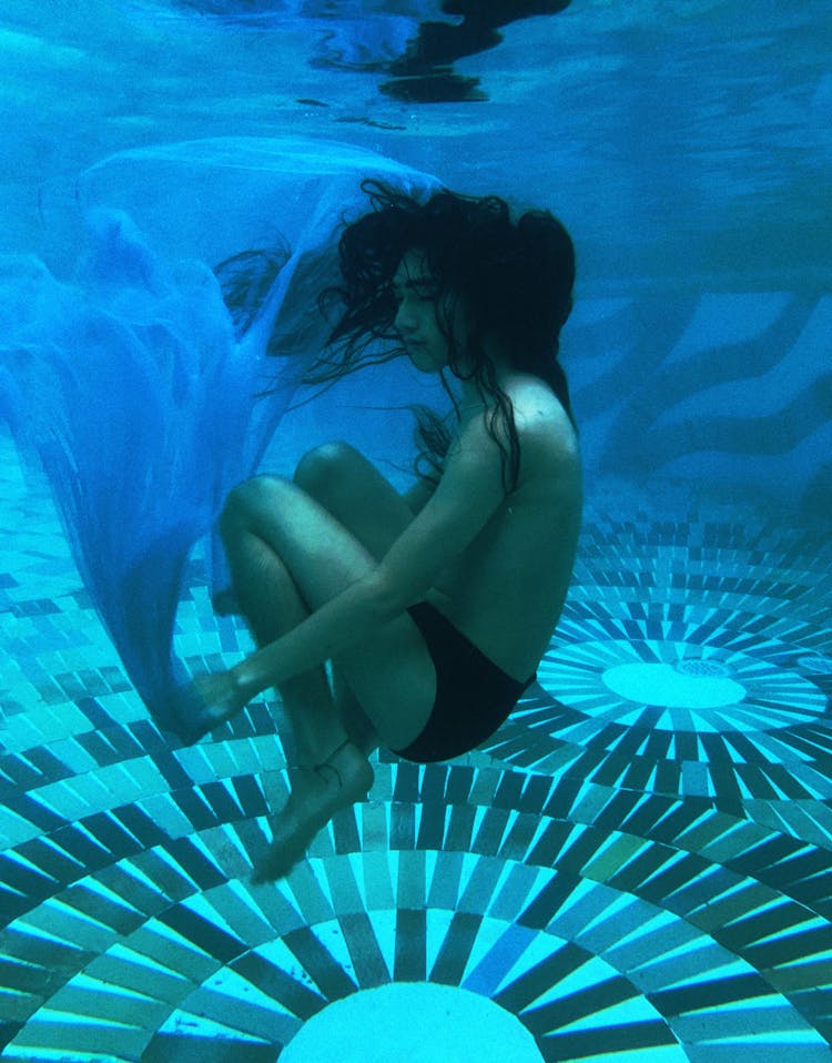 Young Shirtless Ethnic Man Swimming Underwater With Closed Eyes